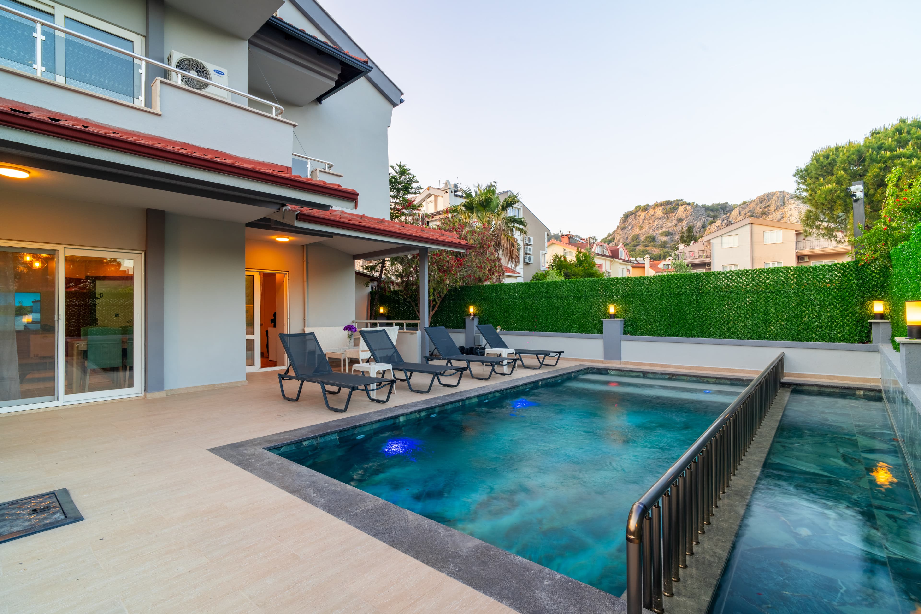 Mare Perla villa — havuz, ev cephesi ve dağ silueti